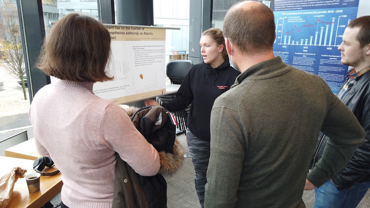 a student presents her poster to the audience during the viewing session